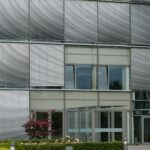 Façade d'un bâtiment commercial moderne équipée de stores vénitiens extérieurs métalliques et de fenêtres en aluminium installés par PROMETAL TMF.