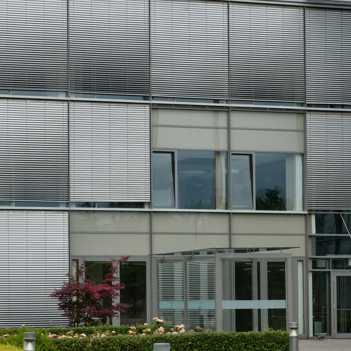 Façade d'un bâtiment commercial moderne équipée de stores vénitiens extérieurs métalliques et de fenêtres en aluminium installés par PROMETAL TMF.